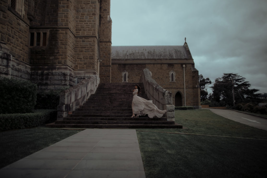 Bride at the steps of a church, her Leanne Marshall silk chiffon skirt moves gracefully with the wind.